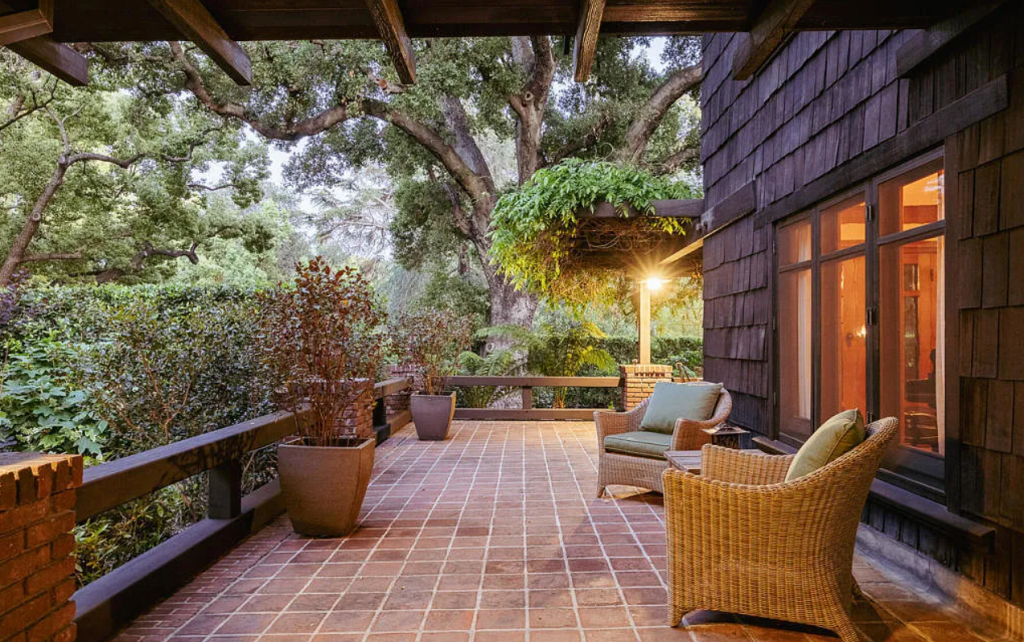 Back patio of the Louise C. Bentz House with outdoor seating, pergola structure, mature landscaping, and brick pathways