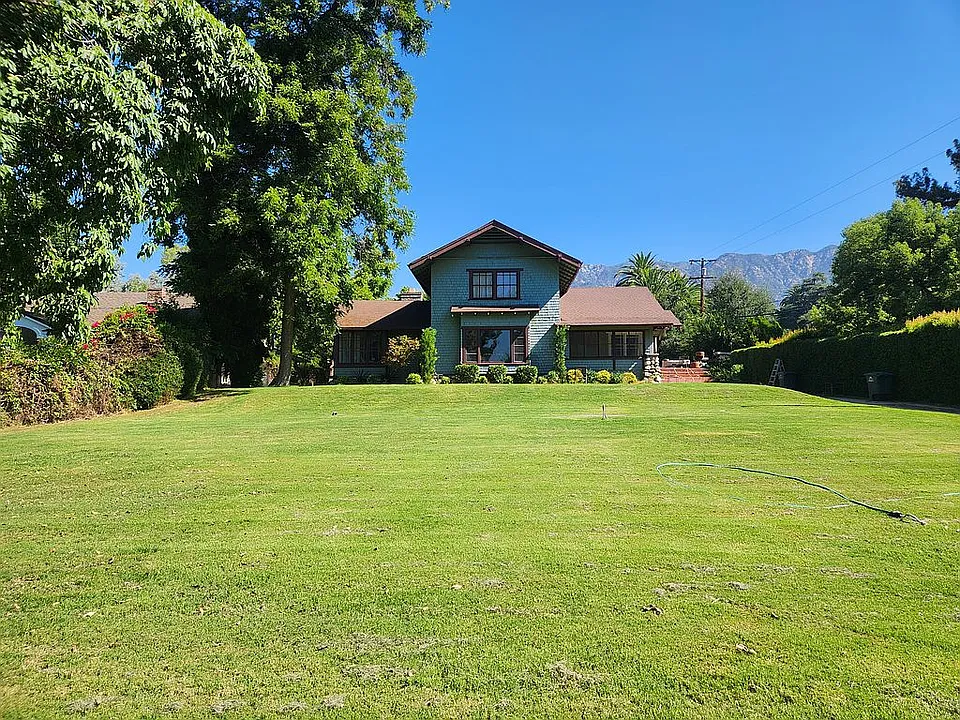 A wide shot of the backyard of the William A. Bowen House, with a large green lawn and mountains in the distance.
