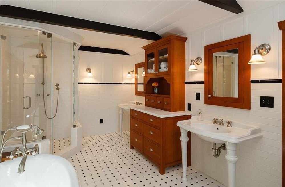 Gallery of two images showing the Edgar W. Camp House private spaces: a bathroom with exposed beam ceiling, custom wood cabinetry, and period-appropriate fixtures, and a bedroom featuring exposed structural beams, rustic wood doors, and Arts and Crafts lighting.