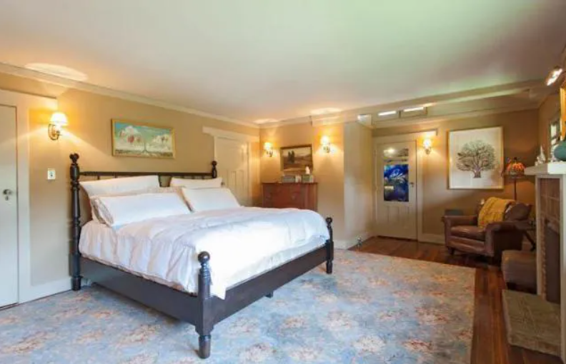 A bright bedroom with white walls and simple wood furniture in the Louise T. Halsted House.