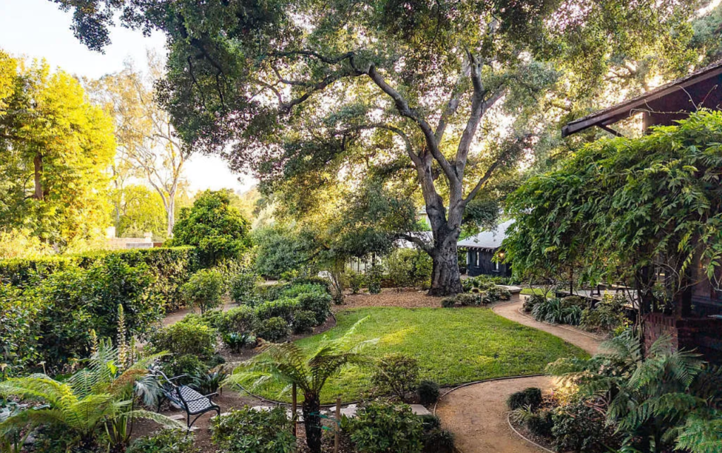 Distant backyard landscaping view of the Louise C. Bentz House showing mature trees, garden beds, and property layout
