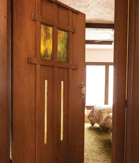 Contemporary interior photograph showing a handcrafted wooden door with stained glass panels and exposed beam ceiling in the Cora C. Hollister House, demonstrating Greene & Greene's commitment to authentic craftsmanship.