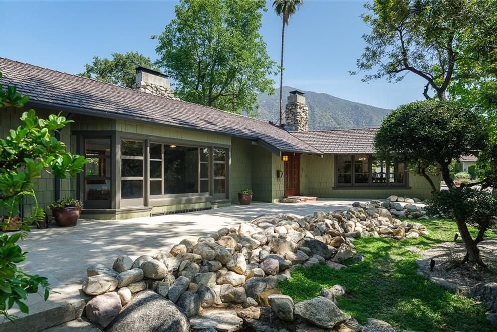 Gallery of two images showing the Edgar W. Camp House entrance: the entrance terrace with extensive boulder landscaping and mountain views, and a close-up of the front door with its distinctive wooden grid design and brick entry platform.