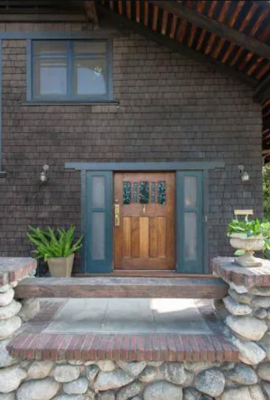 A detailed view of the wooden front door and covered terrace of the Louise T. Halsted House.