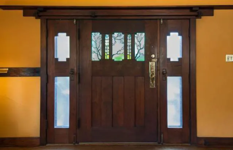 The interior side of the front door of the Louise T. Halsted House, showing the detailed woodwork and art glass window.