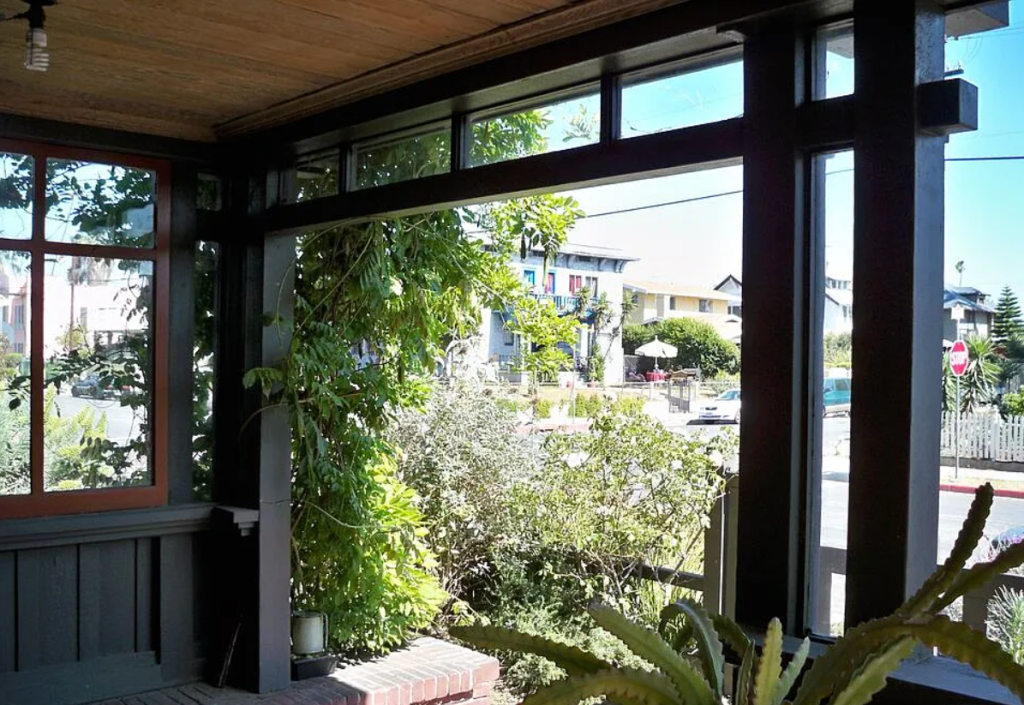 A close-up photograph of the front porch of the Miss Lucy E. Wheeler House, showing its exposed beams and joinery.