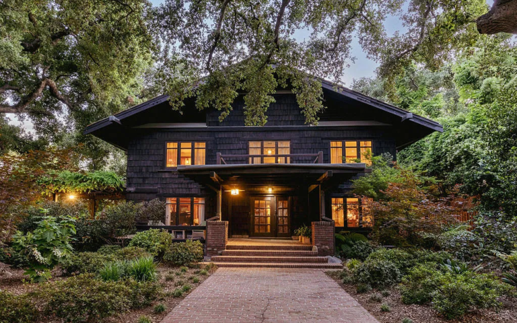 Front walkway of the Louise C. Bentz House with stone path, mature plantings, entry steps, and Arts and Crafts details