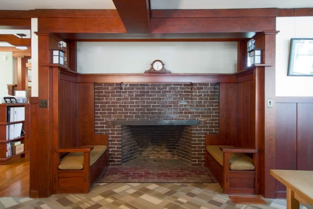 Interior view of the Samuel P. Sanborn House inglenook featuring a brick fireplace with built-in wooden benches and custom millwork in rich wood tones.