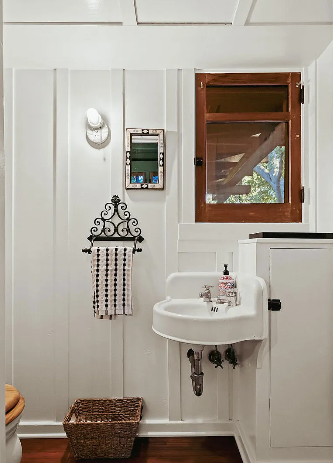 Third bathroom in the Louise C. Bentz House with white tile, pedestal sink, vintage fixtures, and wood wainscoting