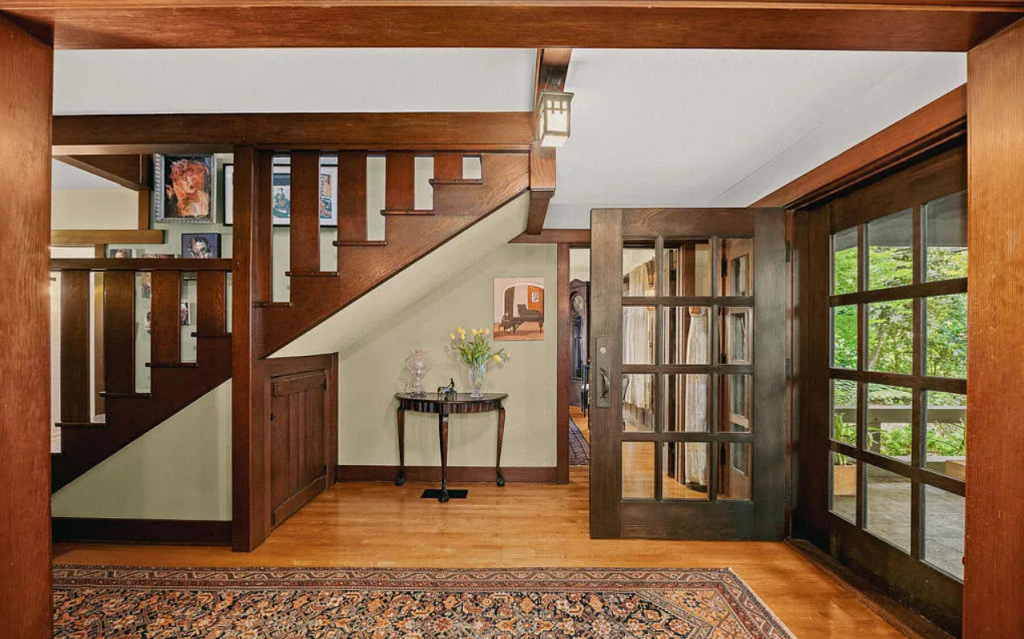 Main entryway of the Louise C. Bentz House with hardwood floors, staircase, wood paneling, and Arts and Crafts details