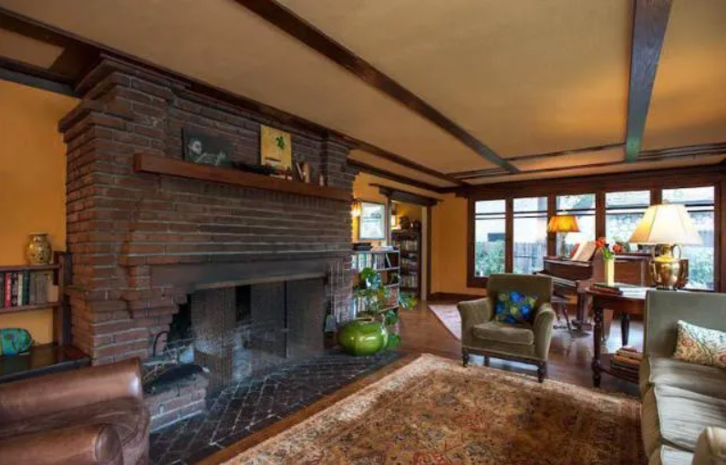 A close-up of the large brick fireplace and built-in wooden inglenook bench in the living room.