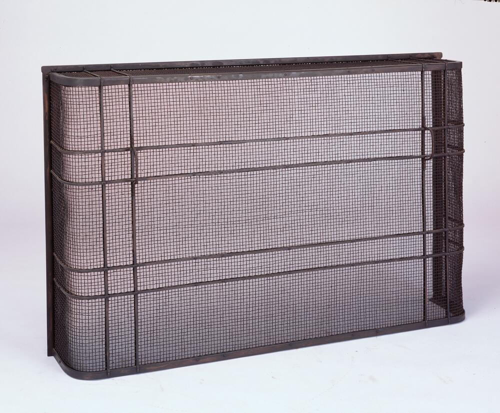 Custom-designed fireplace screen with delicate metal frame and fine mesh, combining function and aesthetic beauty. The screen demonstrates Arts and Crafts principles of elevating utilitarian objects through thoughtful design, with proportions harmonizing with the fireplace surround.
