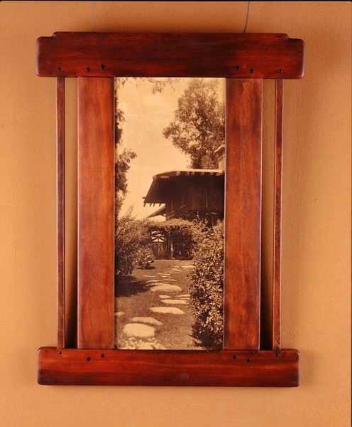 Picture frame in Honduras mahogany holding a historical photograph of the Gamble House exterior. The custom frame demonstrates how the Greenes designed even frames for house documentation, maintaining design consistency throughout all decorative elements.