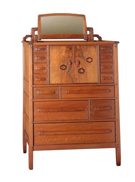 Greene and Greene designed chiffonier from the Gamble House crafted by Peter Hall Manufacturing Company in Honduras mahogany and black walnut, featuring a tall vertical form with tilting mirror at top, eight drawers of varying sizes with cloud-lift copper pulls, central cabinet doors with figured black walnut panels decorated with silver and abalone shell inlay depicting oak leaves and acorns, square ebony pegs throughout, tapered legs, and the signature rounded edges and handcrafted joinery that characterize the ultimate bungalow furniture