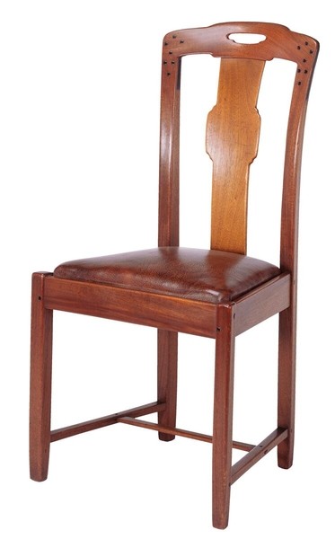 Greene and Greene designed dining room chair from the Gamble House crafted by Peter Hall Manufacturing Company in Honduras mahogany, featuring a tall back with cloud-lift cutout handle at the crest rail, vertical splat with organic curved form, square ebony pegs securing the joinery, tapered legs with stretchers, and a brown leather upholstered slip seat, demonstrating the brothers' synthesis of Arts and Crafts principles with Asian-inspired design elements