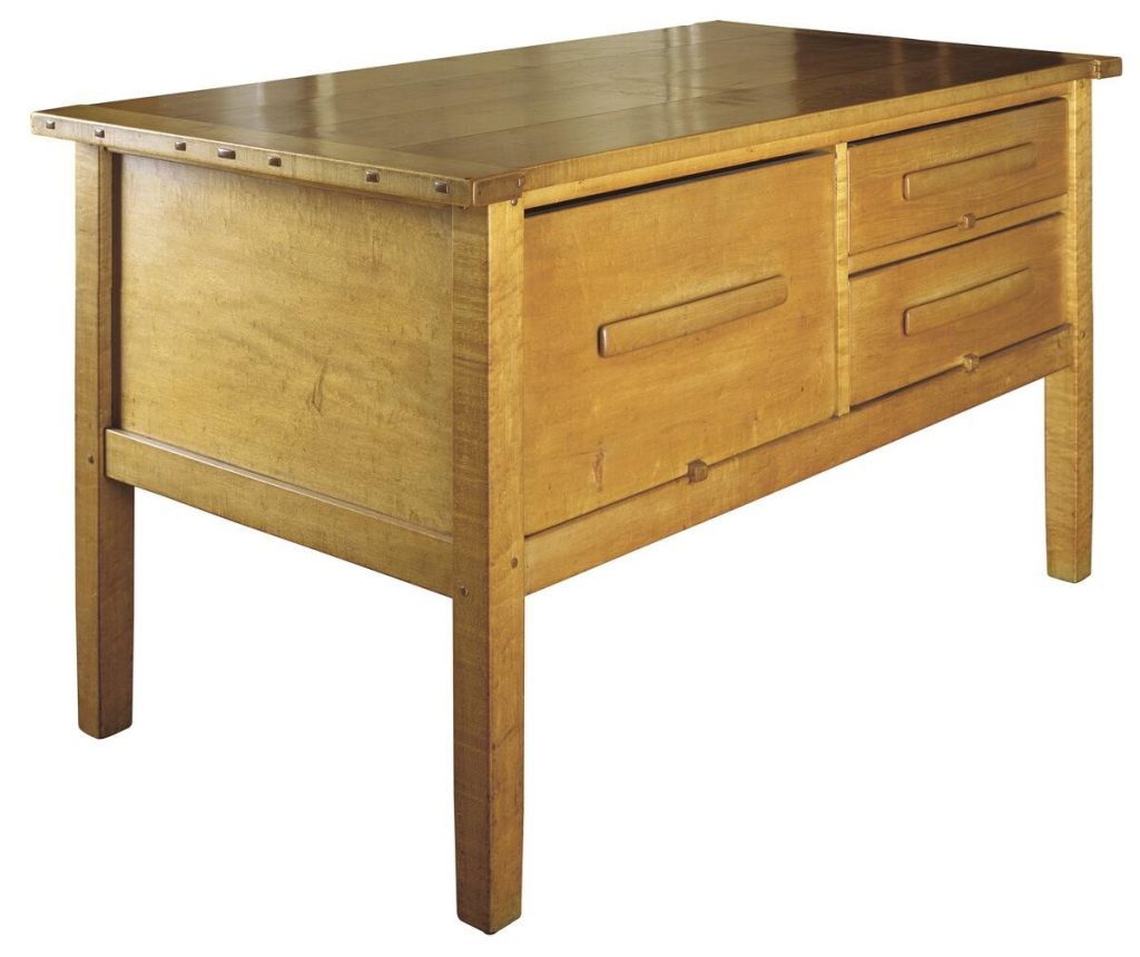 Maple kitchen island workstation with thick plank top and sturdy tapered legs. Features multiple drawers with simple horizontal pulls, visible joinery details, and robust construction designed for food preparation. The natural maple finish showcases the wood's characteristic light grain pattern.