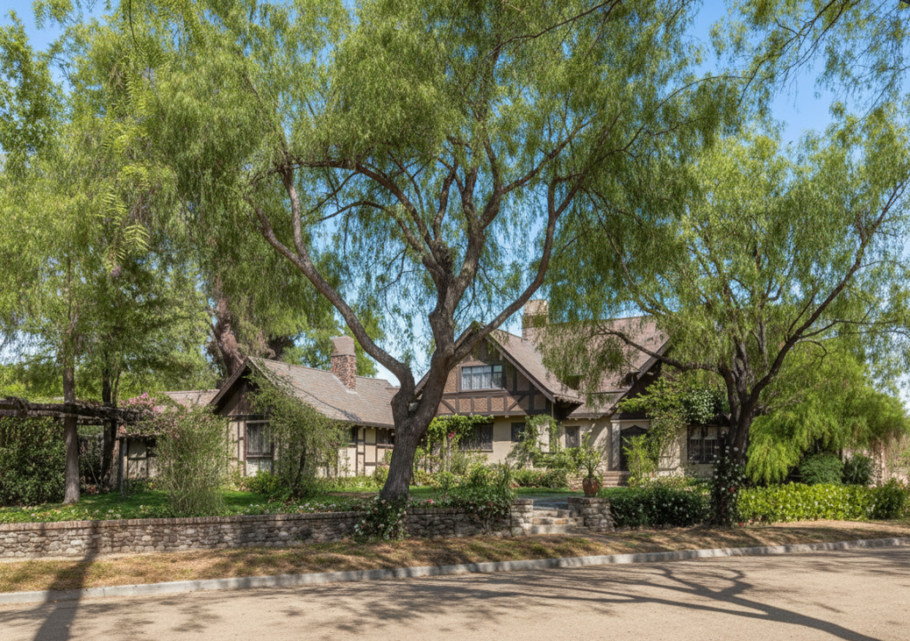 Exterior view of Craftsman bungalow with dark wood shingles, cream stucco, stone chimney, and landscaped grounds