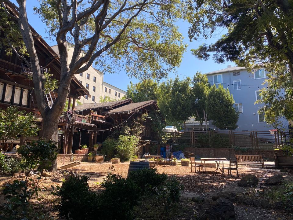 Thorsen House backyard showing timber bridge, clinker brick terraces, wood-shingled walls, and sheltered garden space