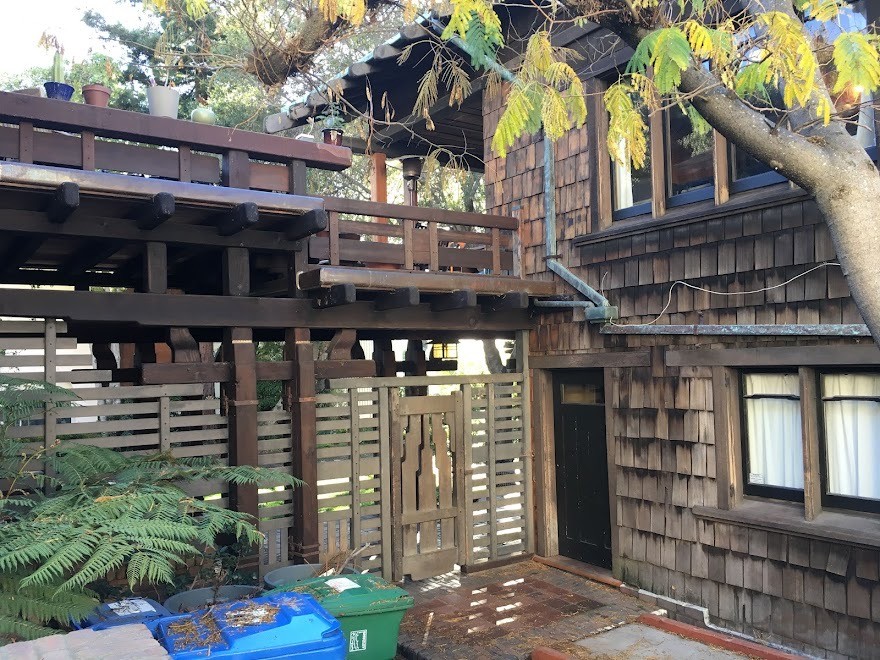 Wooden gate leading to Thorsen House backyard with timber posts, clinker brick walls, and Greene & Greene joinery