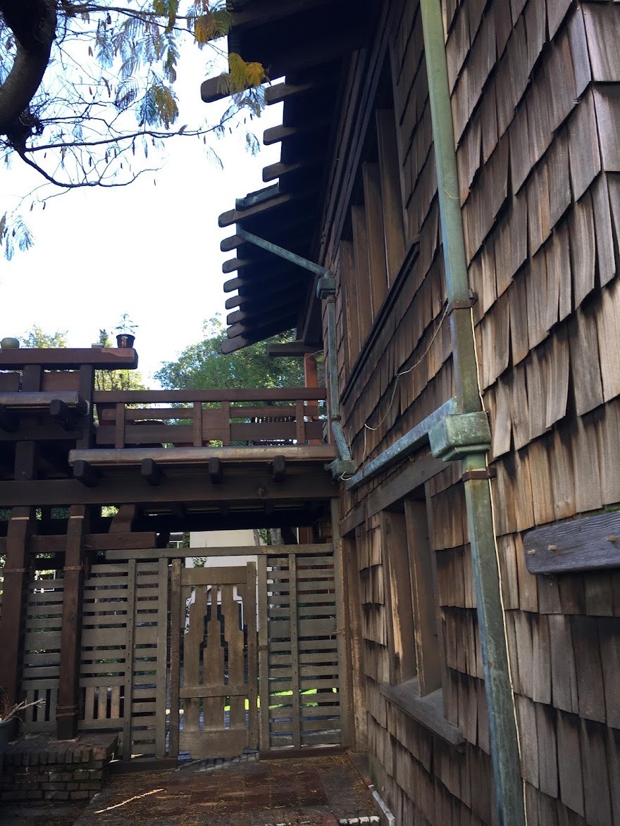 Alternate view of wooden gate to Thorsen House backyard with timber frame, clinker brick base, and architectural details
