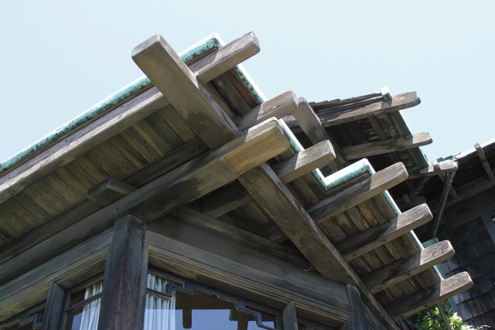 Close-up of Thorsen House dining room bay window eaves showing timber rafter tails, corbels, and copper flashing details