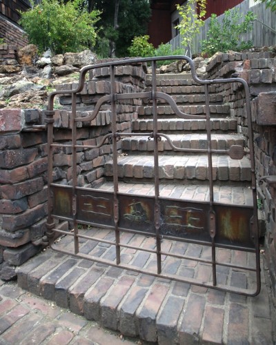 Wrought iron entrance gate to Thorsen House with Viking ship panel, clinker brick stairs, and architectural ironwork