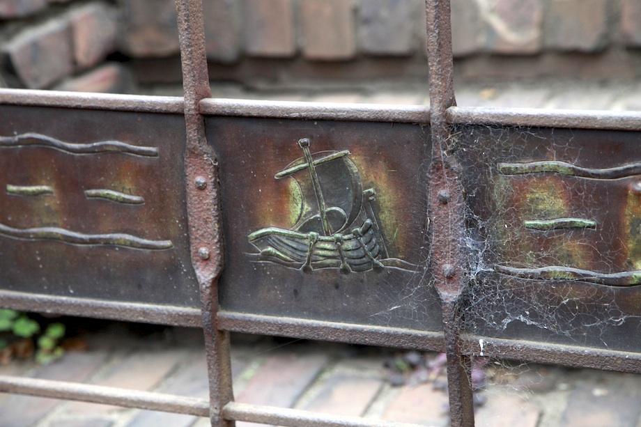 Close-up of Viking longship repoussé panel in Thorsen House wrought iron gate, honoring Norwegian maritime heritage