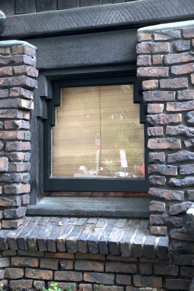 Thorsen House basement window with clinker brick surround, painted wood frame, and articulated corner details