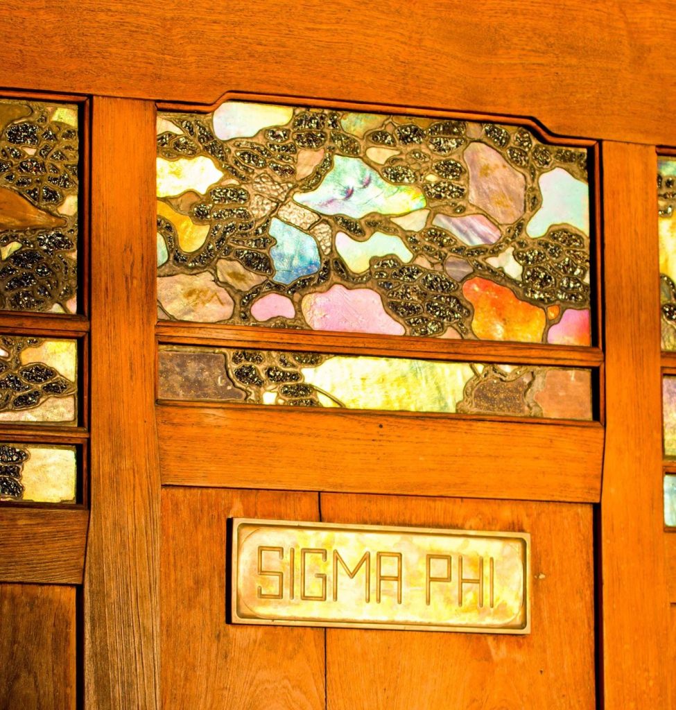 Front door art glass panel with cloud lift pattern, iridescent abalone shell inlay, and Sigma Phi brass nameplate
