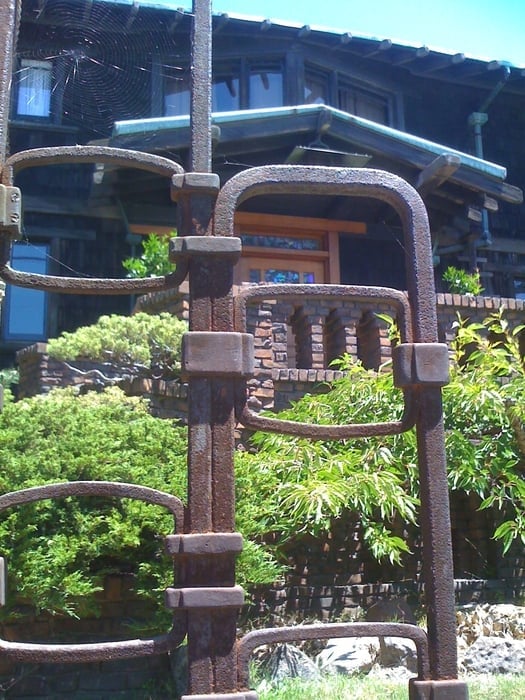 Detail of Thorsen House wrought iron gate showing complex interlocking ironwork, Viking ship panel, and clinker brick piers