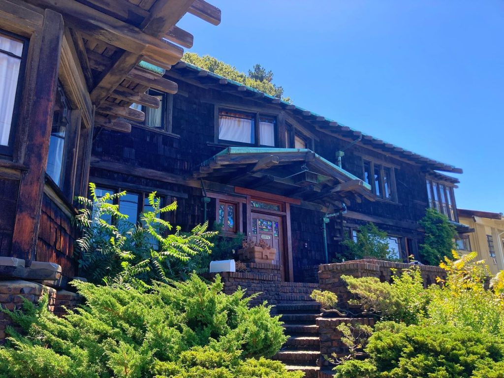 Northwest corner view of Thorsen House showing brick stairs, front door with art glass, and timber-framed overhangs