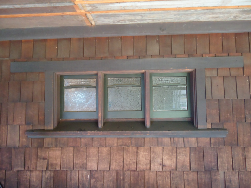 Trio of Thorsen House bathroom casement windows with textured privacy glass, art glass transoms, and painted wood frame