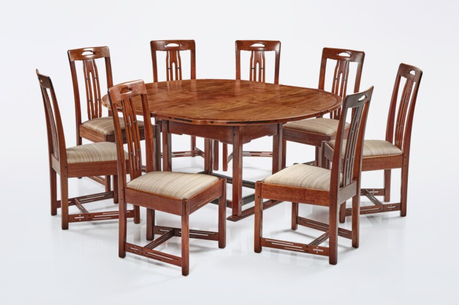 Complete dining set with round table and ten matching ladder-back chairs with upholstered seats in Arts and Crafts style.
