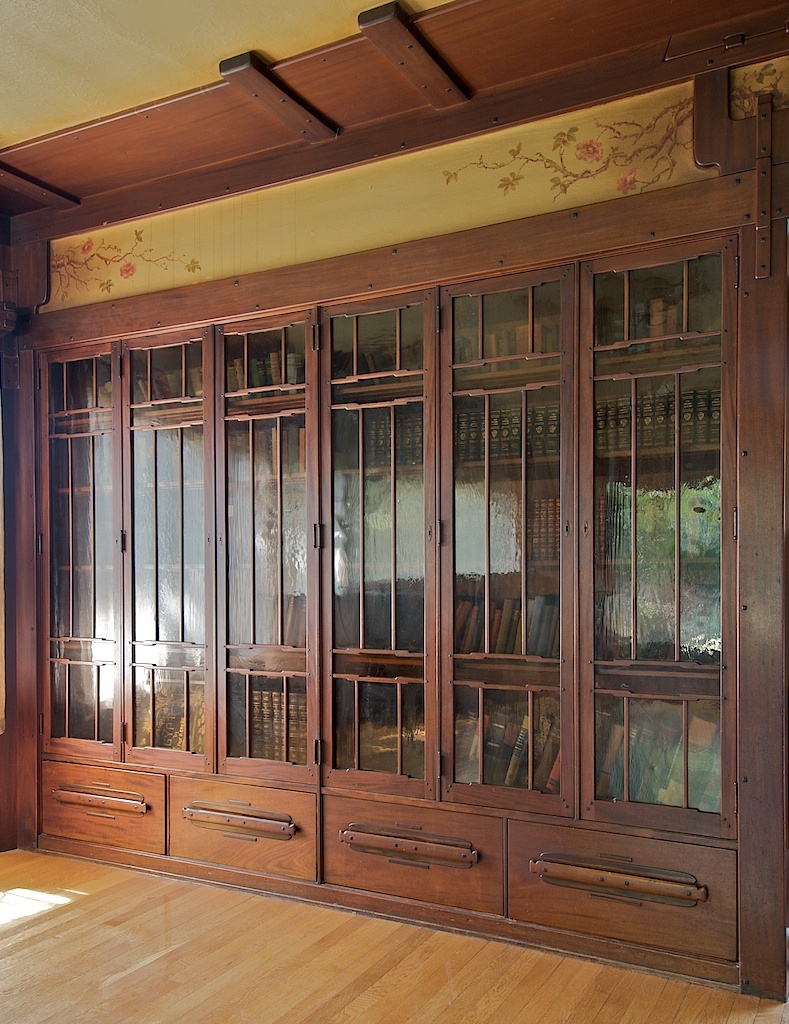 Thorsen House built-in bookcases with glass doors, copper hardware, painted frieze above, and Arts & Crafts joinery