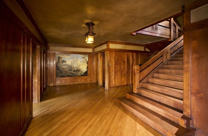 Thorsen House entrance hall with harbor painting, hanging lantern with leather straps, staircase, and oak paneling