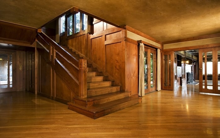 Thorsen House entrance hall showing staircase with chunky newel post, oak flooring, and Arts & Crafts woodwork details