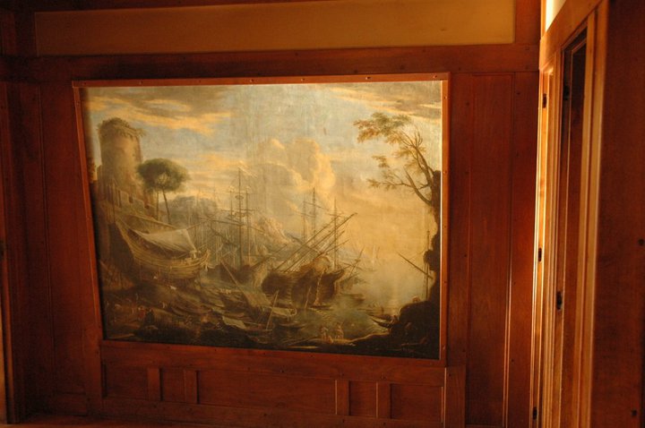 Entrance hall harbor scene painting set in mahogany paneling, depicting ships and maritime activity in muted tones