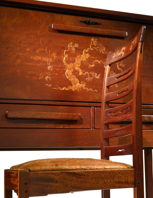 Fall-front desk detail showing floral inlay decoration on drop-front panel with ladder-back chair featuring leather seat.