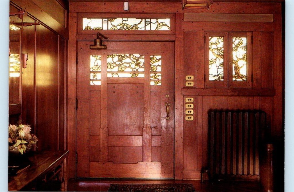 Interior view of Thorsen House front door with iridescent art glass panels, bronze hardware, and mahogany woodwork