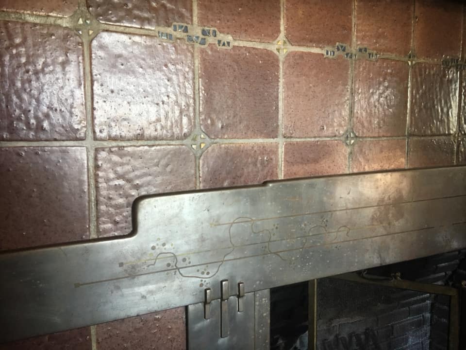 Close-up of Thorsen House living room fireplace with textured tile, copper mantel, and cloud lift art glass accents