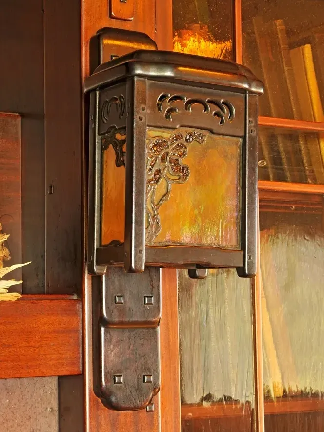 Thorsen House fireplace mantel sconce with organic tree design in amber glass, and cloud lift metalwork.