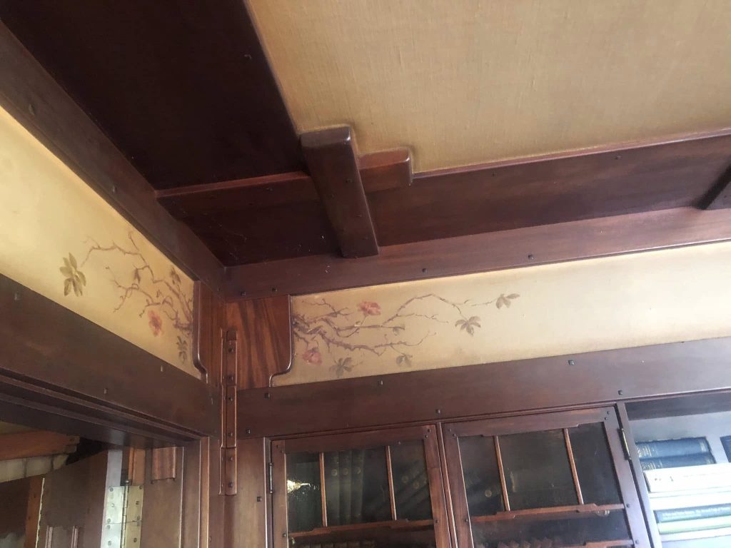 Thorsen House living room painted frieze by Charles Greene showing trailing roses, exposed beams, and built-in bookcases