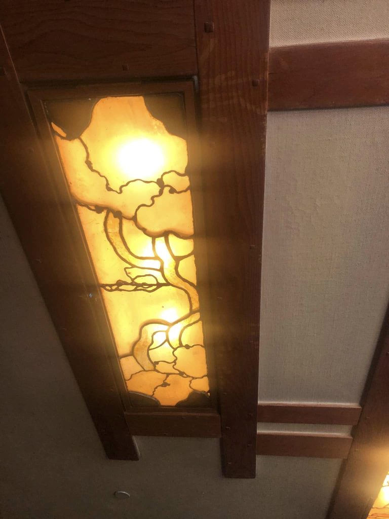 Close-up of illuminated recessed ceiling fixture at Thorsen House with cloud lift art glass and timber frame detail