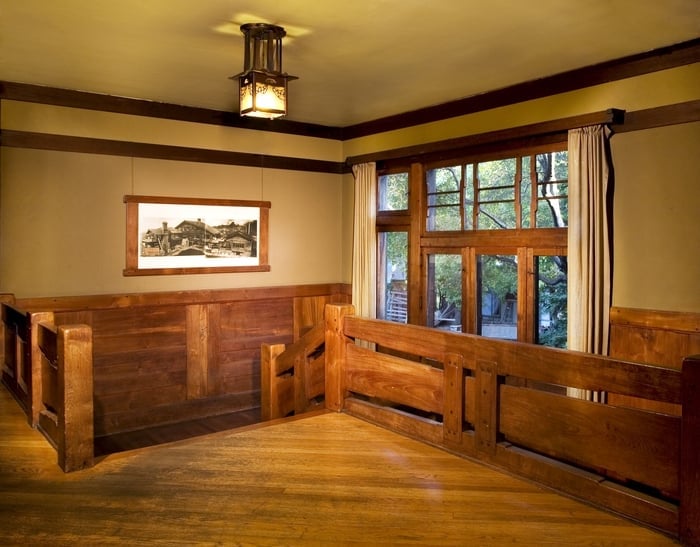 Top of Thorsen House stairway with second-floor landing, built-in seating, historic photograph, and ceiling lantern