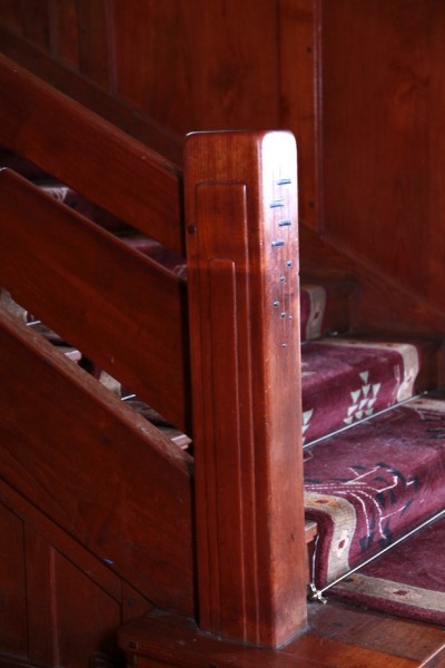 Thorsen House chunky stairway newel post with ebony and fruitwood inlay, simple lines, and Arts & Crafts design
