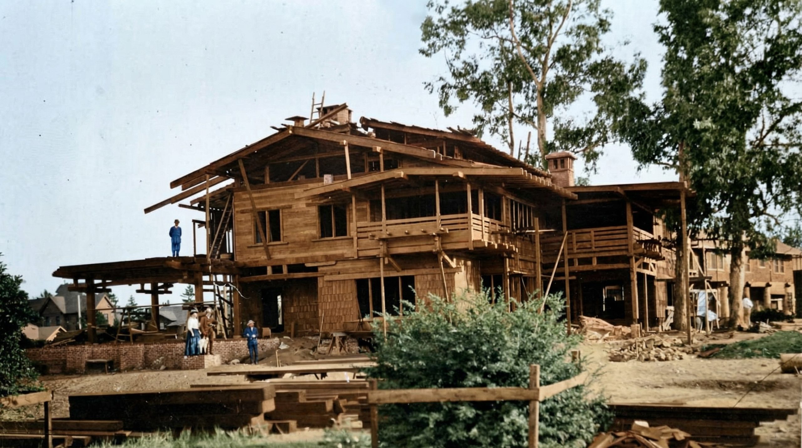 Historic colorized construction photograph of the Gamble House circa 1907-1908, showing the house mid-construction. 