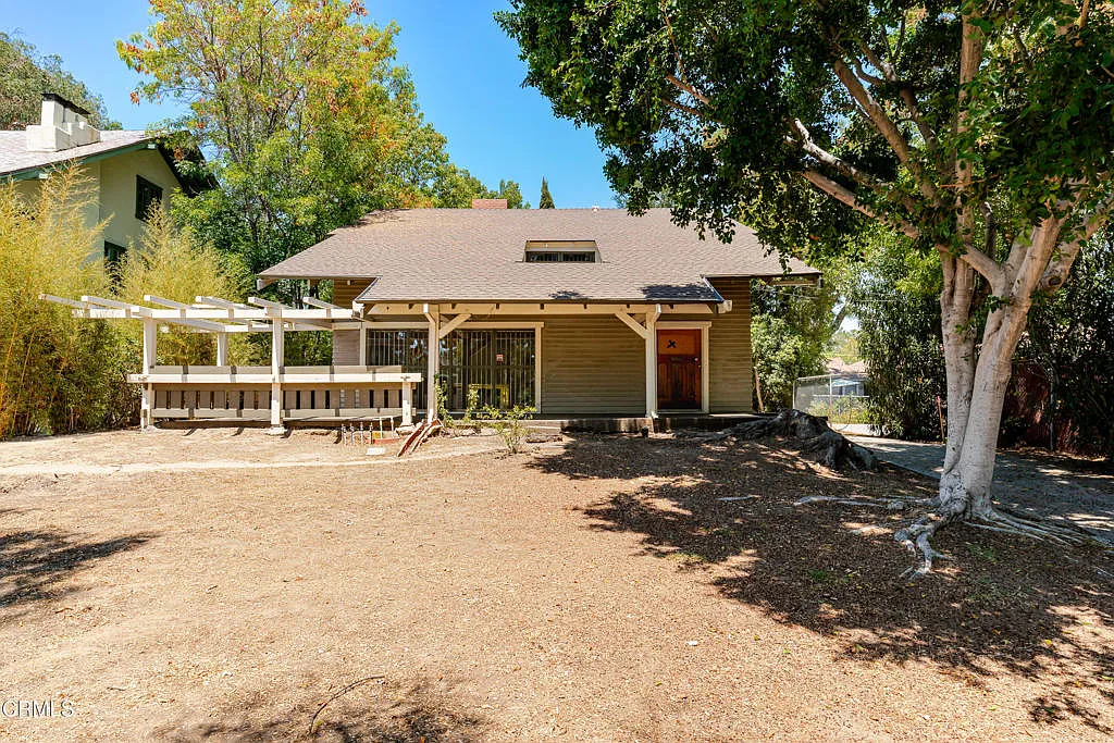 Front elevation showing Francis F. Rowland house with white pergola, natural wood siding, central dormer, and dirt driveway