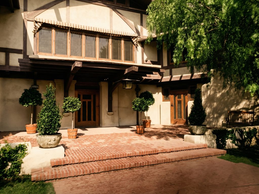 Historic colorized photo of the Laurabelle A. Robinson House front entry with original landscaping and stone walkway