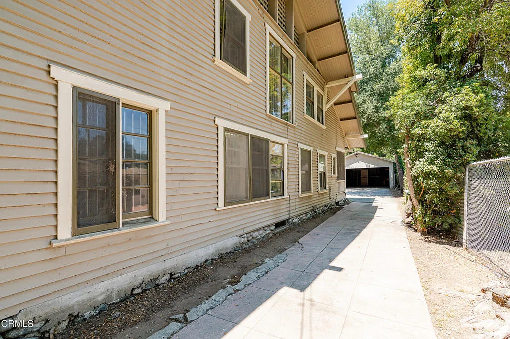 North facade of Francis F. Rowland house with natural wood horizontal siding, white-trimmed windows, exposed rafter tails, and concrete walkway