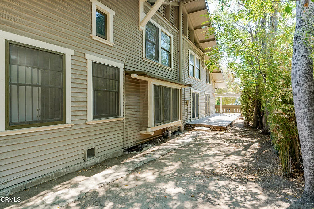 South facade of Francis F. Rowland house showing two-tone wood siding, white-trimmed windows, exposed beams, gravel path, and mature trees